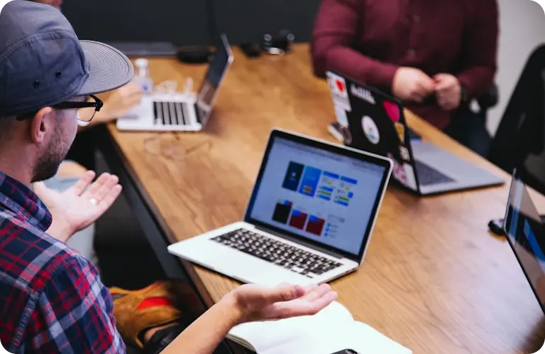 a group of people sitting at a table with laptops